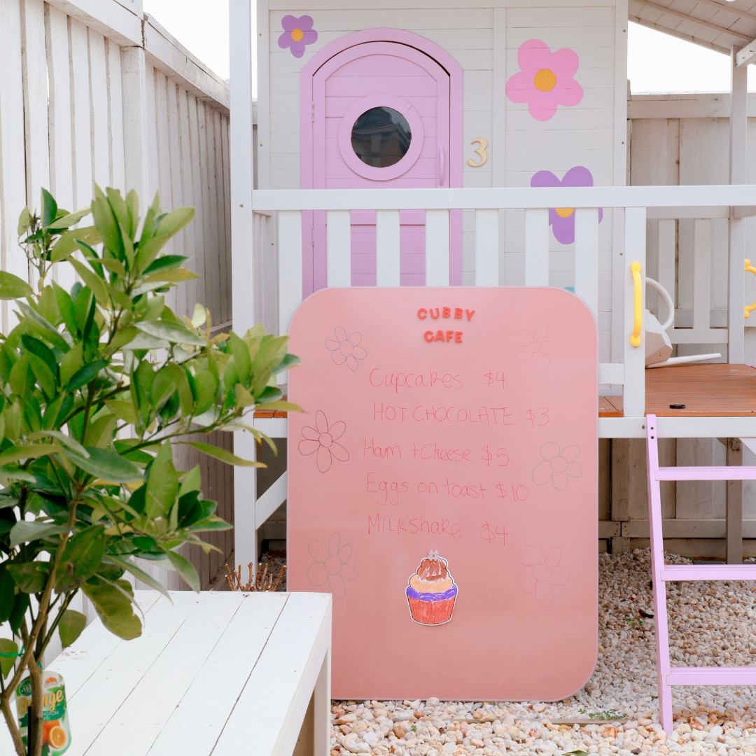 Maynetic weatherproof board next to a children's outdoor play cubby. 