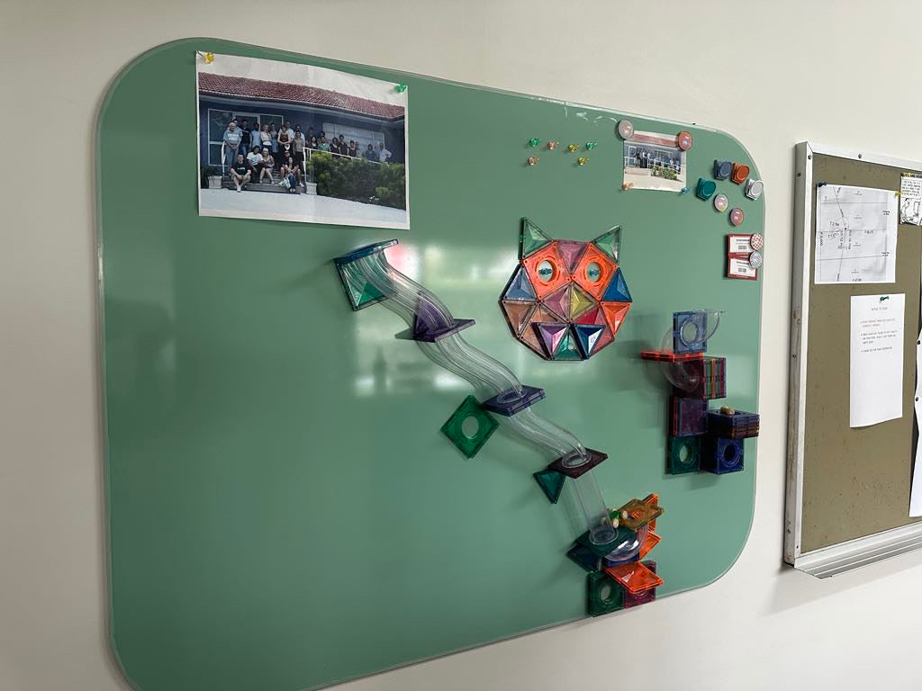 A stylish office whiteboard set up for fun and work next to an old unattractive office pin board.