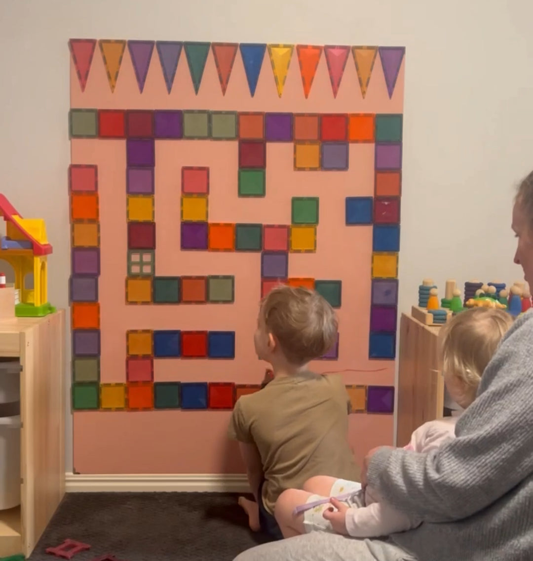 A parent and child sitting together, while an older child is using the board for a fun activity.